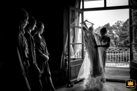 Bride shares a moment with her bridesmaids as they are ready to help her finish getting dressed at the picturesque Domaine des Saints Pères, preparing for the day's wedding festivities.